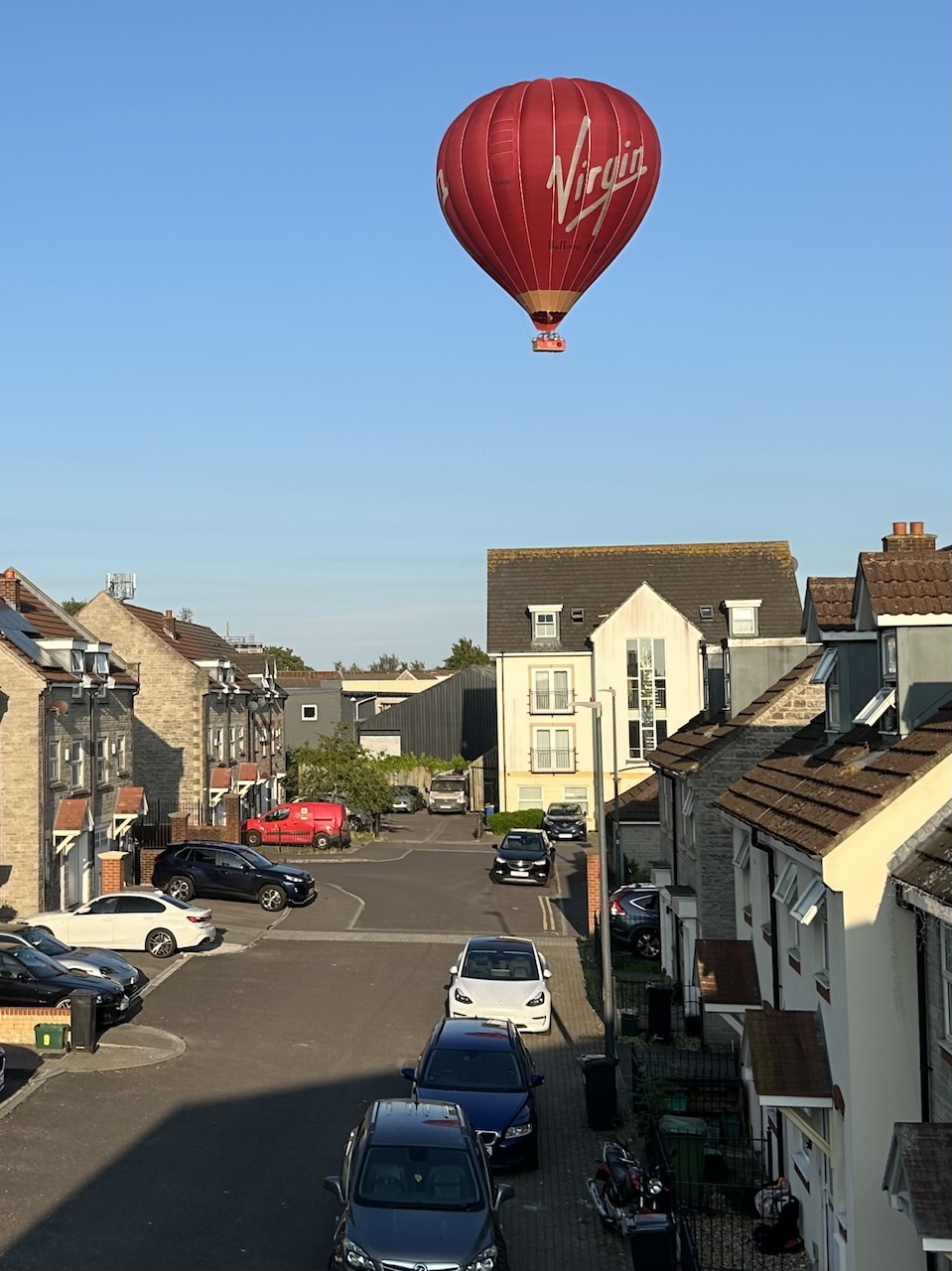 a hot air balloon flying incredibly low over a residential street