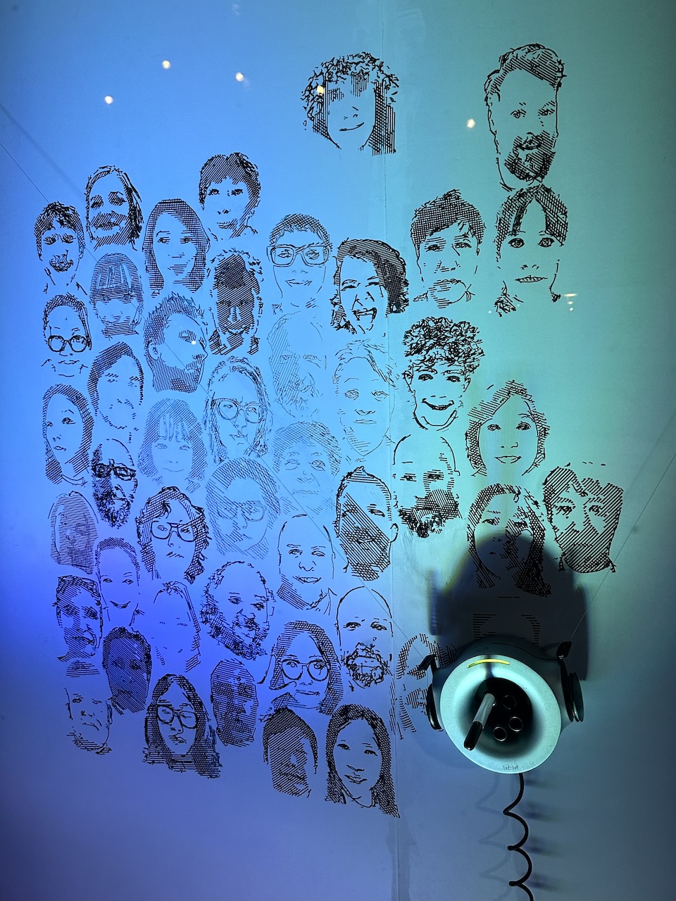 a blue-lit wall of robot-drawn portraits