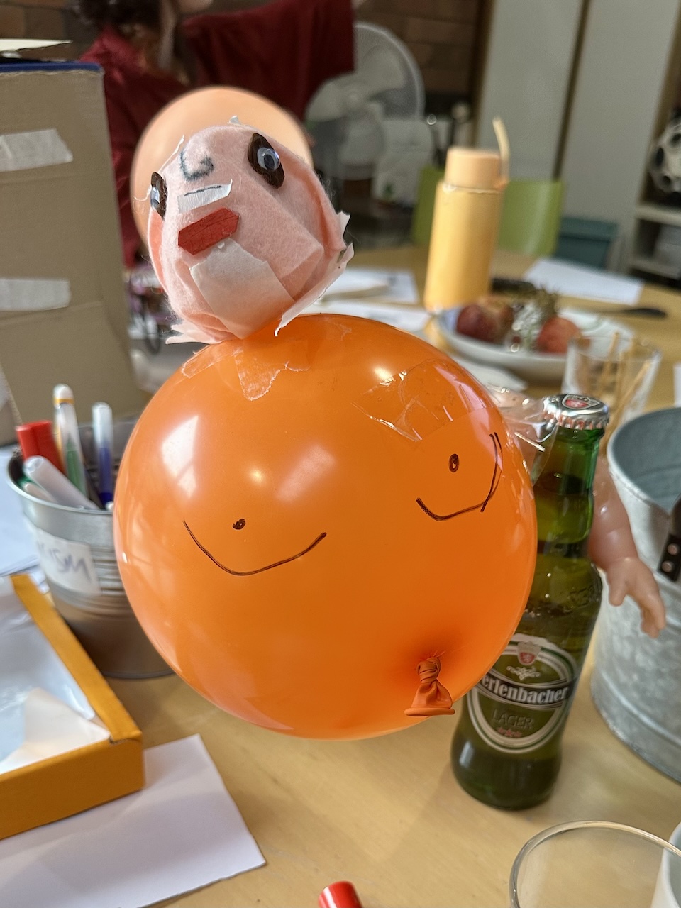 a creepy figure made out of a balloon and hugging a beer bottle